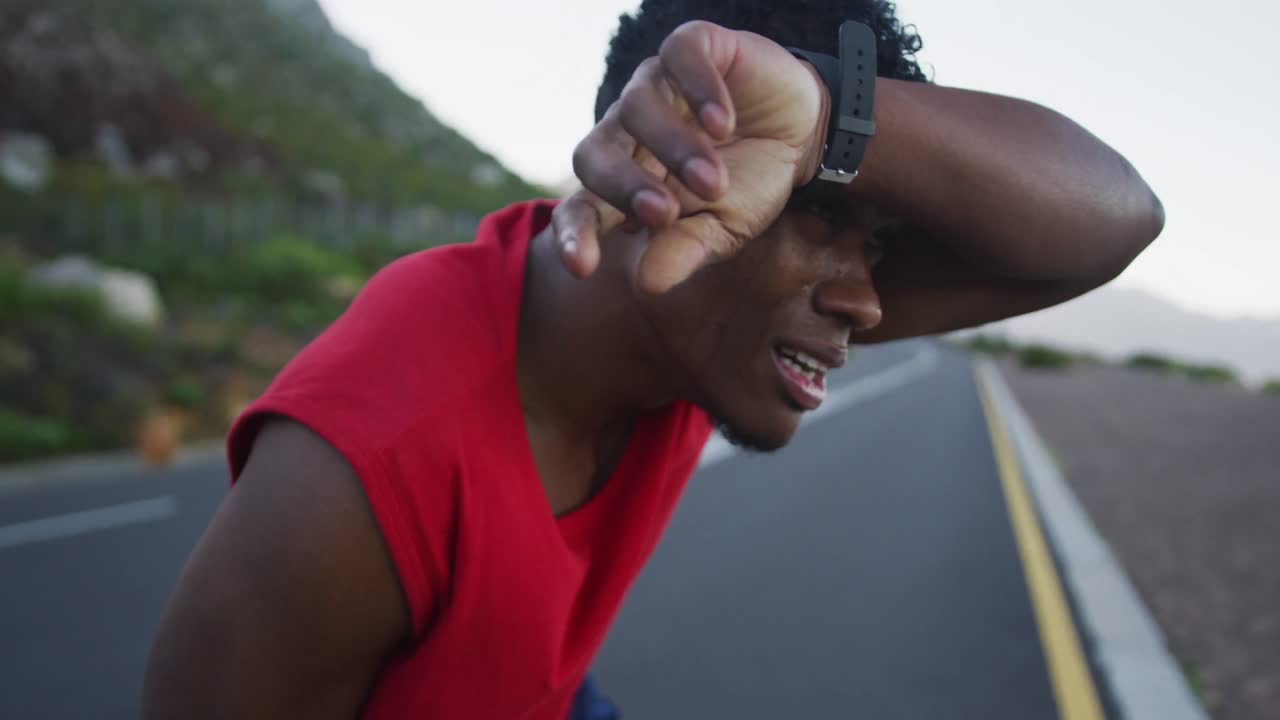 Uomo afroamericano stanco che si prende una pausa dalla corsa per strada.