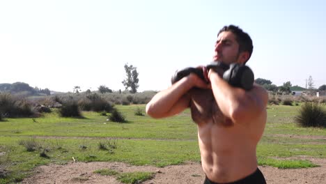 muscular man performing squats training legs with kettlebell