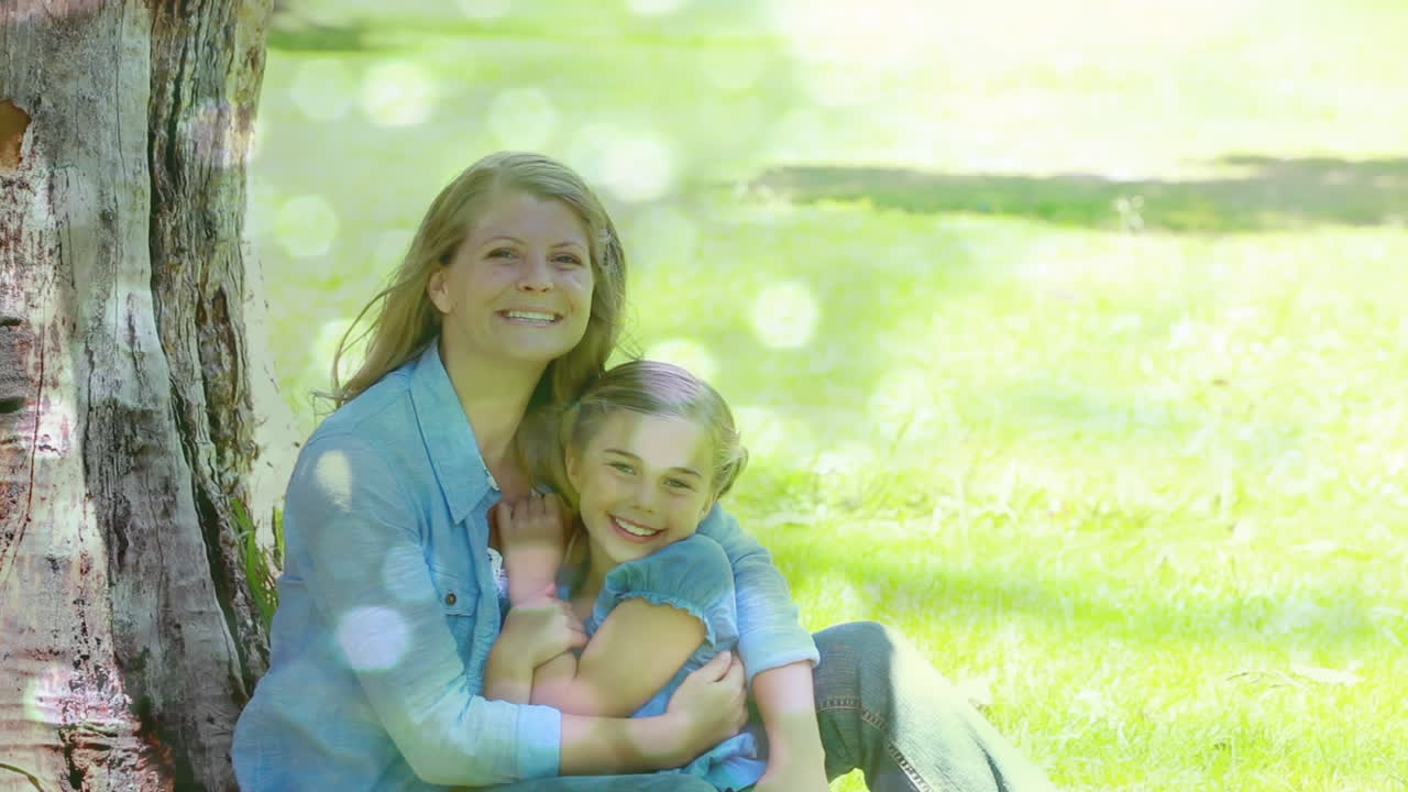 animación de puntos brillantes sobre una madre caucásica feliz con su hija acurrucada en el jardín