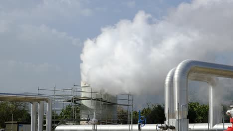 geothermal station with steam and pipes in the rainforest. billowing steam from smoke stack filling sky, buharkent, turkey