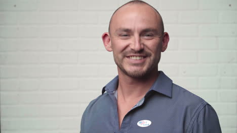 Man-Walks-in-and-Puts-Voting-Sticker-on-Shirt,-Smiling-Proudly