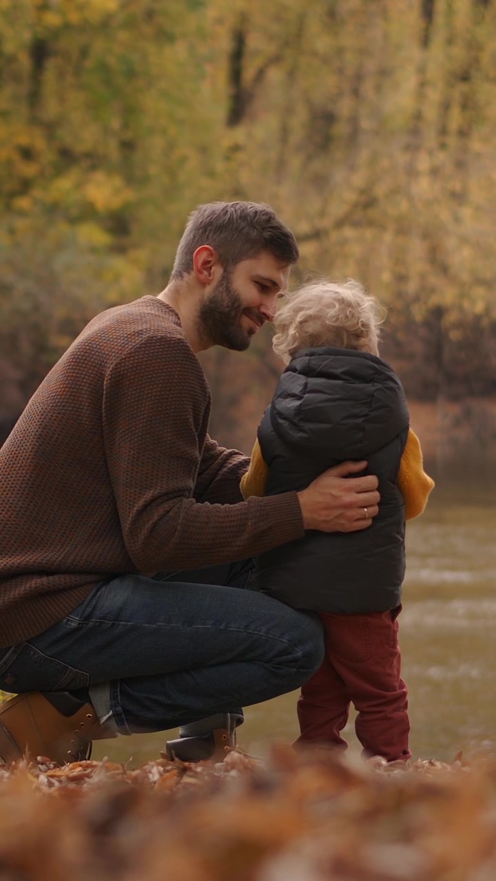 Padre e figlio piccolo che creano un legame vicino a un fiume in autunno