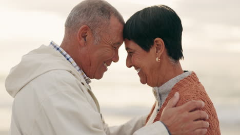 old couple, forehead touch and hug while at beach