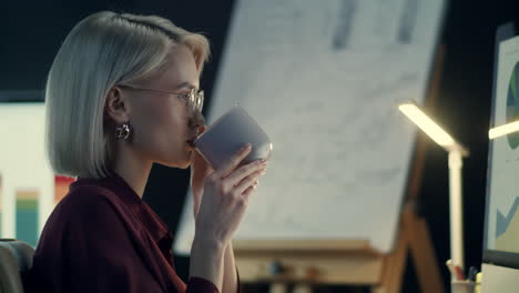 concentrated business woman drinking coffee front computer in night office