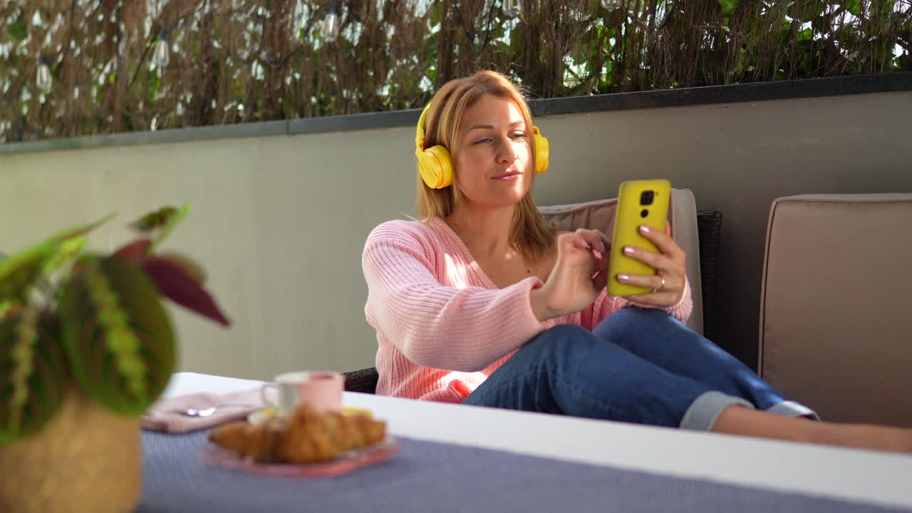 Woman Relaxing with Headphones and Mobile Phone on Balcony