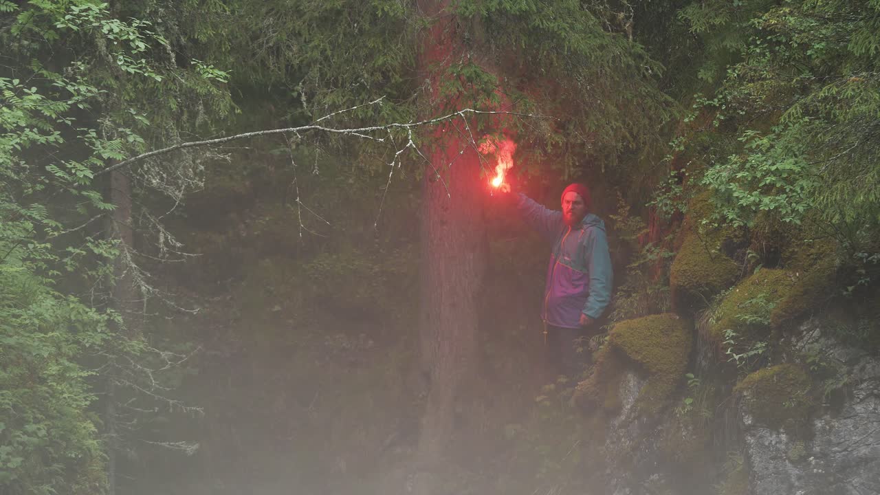 hombre con llamarada roja en el bosque de niebla