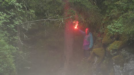 man with red flare in misty forest