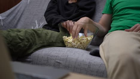 Anonymes-Paar-Sitzt-Auf-Dem-Sofa-Und-Isst-Popcorn