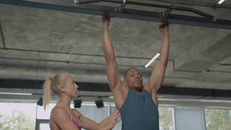 Vista-Frontal-De-Una-Monitora-Caucásica-Y-Un-Atlético-Afroamericano-En-El-Gimnasio.