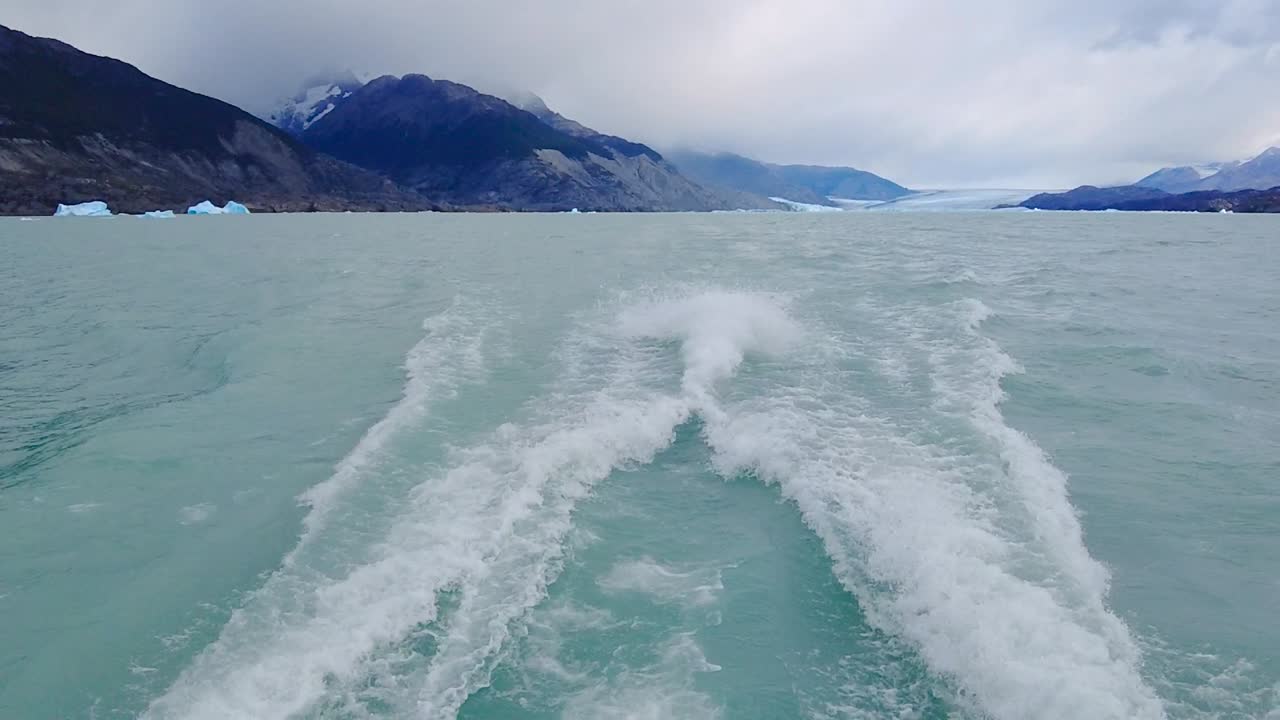 배경에 안개로 뒤덮인 멋진 산들과 함께 프로펠러로 청록색 물을 밀어내는 놀라운 비디오