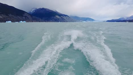 astonishing video of turquoise water being pushed by propellers with a masterful mountains covered by mist in the background