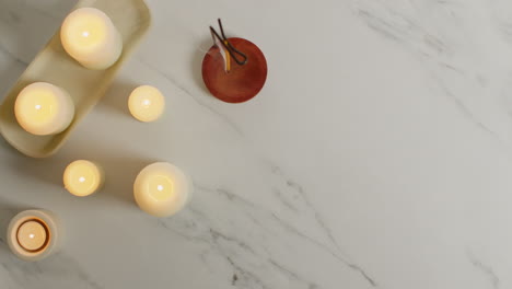 overhead view looking down on still life of lit candles and incense stick as part of relaxing spa day decor