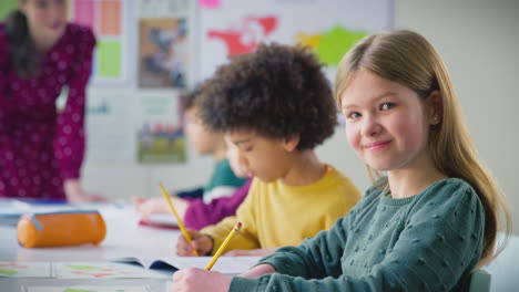 portrait of female student writing in exercise book in multi-cultural classroom