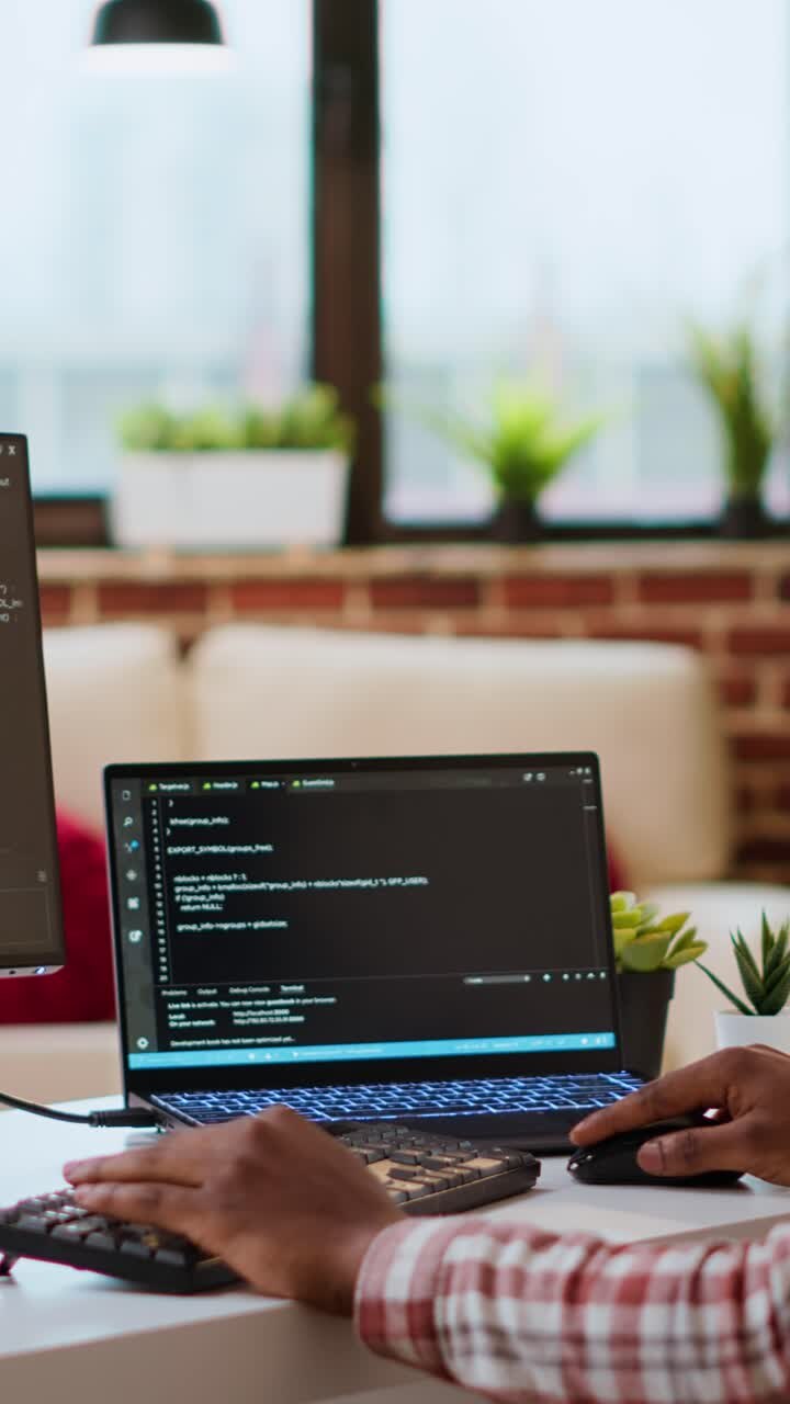 Video Vertikal. Seorang pemuda terlihat memprogram kode perangkat lunak di laptopnya di kantor rumah yang apik