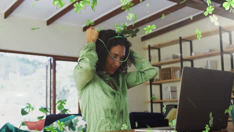 animation of shamrocks falling and biracial woman in shamrock glasses celebrating st patrick's day