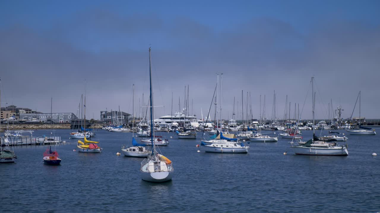 A view of a harbor filled with numerous sailboats and yachts under a cloudy sky.