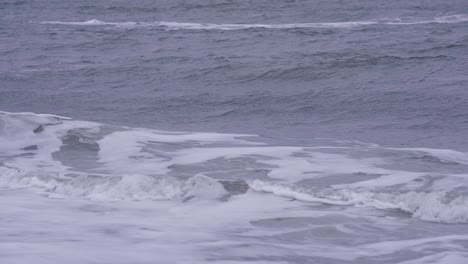 rough stormy ocean waves rolling and crashing onto beach shoreline