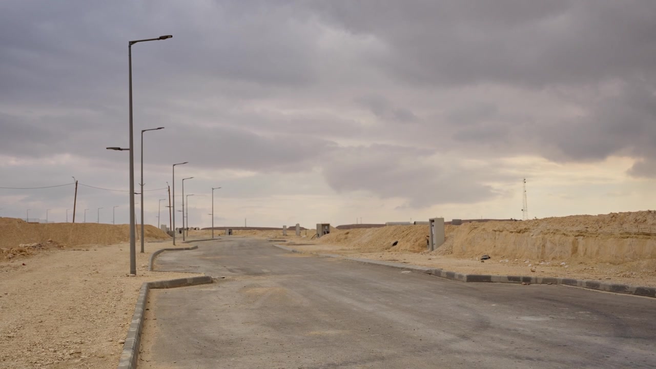 Empty desert development lot with deserted construction and street lamps in remote location outdoors. Apocalyptic abandoned road or ghost town or housing projects in progress and building neighborhood