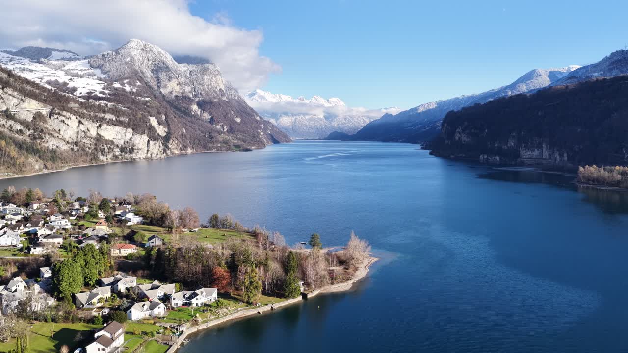 Aerial view of Wessen on the shores of Walensee in Switzerland, showing blue lake waters, surrounding mountains and clear winter sunlight in a peaceful alpine setting