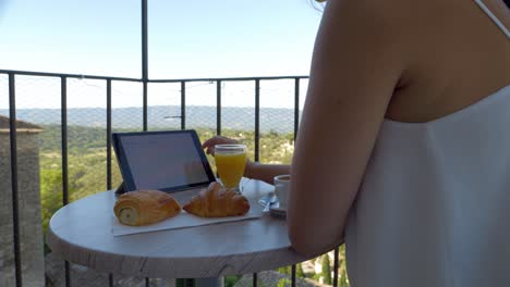 Joven-Empresaria-Que-Trabaja-Mientras-Desayuna-En-El-Balcón-Del-Hotel