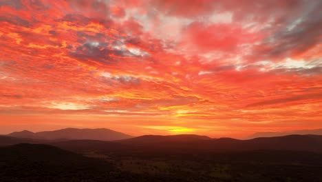 Drone-filming-of-a-spectacular-red-sunset-in-the-Tiétar-Valley-and-with-a-turn-of-the-camera-we-see-the-relief-of-the-mountains-and-the-intense-yellow-of-the-sun,-there-are-vivid-colors-in-the-sky