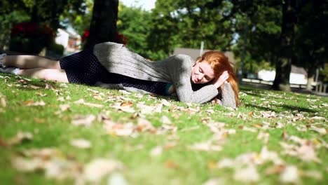 Cheerful redhead relaxing lying on green lawn