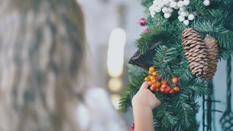 Kleines-Mädchen-Berührt-Beeren-Auf-Dem-Weihnachtskranz-Im-Zimmer