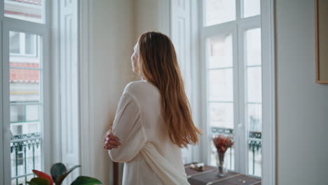 Dancing-woman-swirling-home-closeup.-Relaxed-lady-in-silk-robe-watching-window