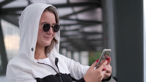 woman in hoodie using smartphone outdoors