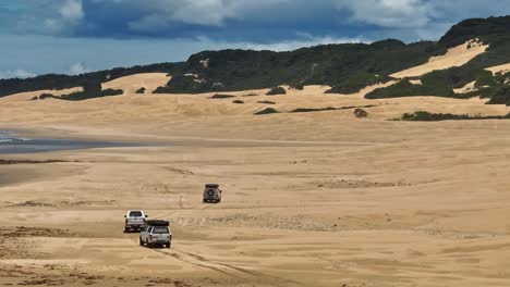 3 cars driving on the beach towards a camp spot in eastern cape, south africa