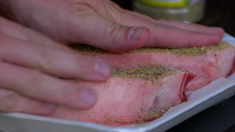 Two-hands-rub-spices-and-salt-into-a-thick-raw-rib-eye-steak-prepping-it-to-be-grilled-in-slow-motion