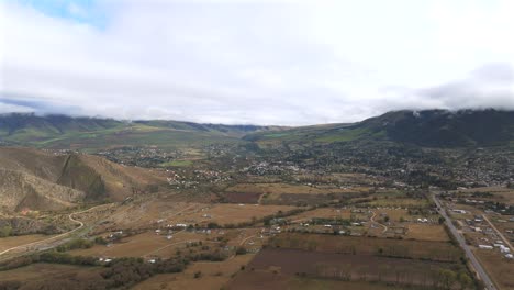 Wide-aerial-drone-shot-of-brown-fieldland-and-hills-during-a-cloudy-day-in-Argentina,-slow-motion-and-copy-space