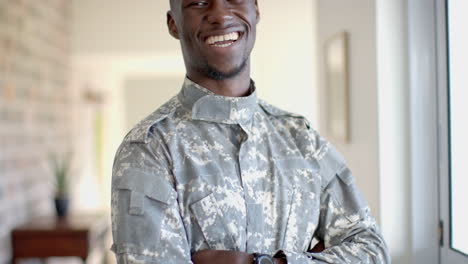 happy african american male soldier standing and smiling in sunny living room, slow motion