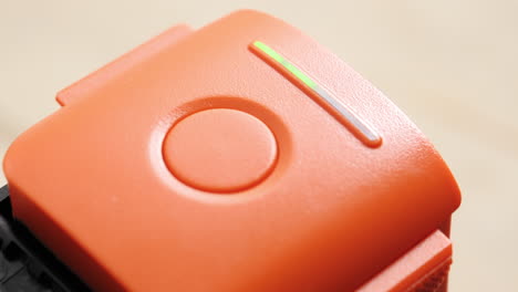 Close-up,-connecting-wire-to-charge-orange-drone-battery,-light-indicator-turning-on