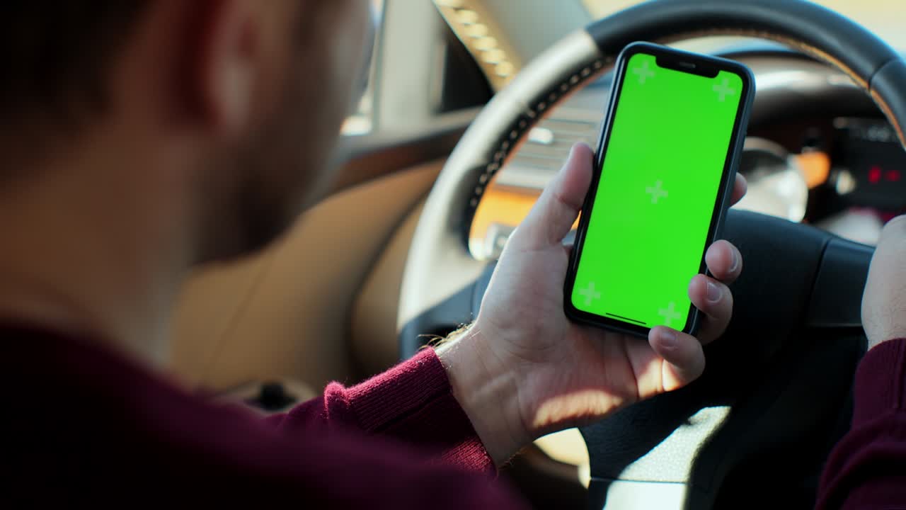 hombre usando teléfono inteligente con pantalla verde llave de croma dentro del coche. concepto: dirección de viaje, búsqueda de dirección, mensaje, ubicación, negocio. vista trasera.