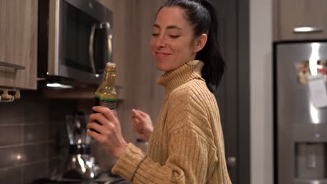 young funny woman joking around while she dances and cooks dinner in her modern kitchen - concept: healthy lifestyle, radiant, date night, silly - medium shot