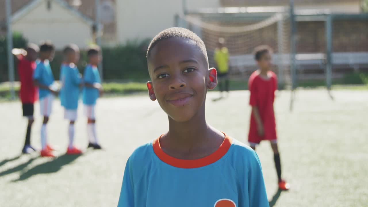 African American soccer kid in blue smiling and looking at camera