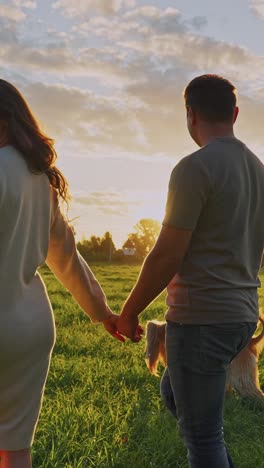 pregnant couple walking hand in hand at sunset
