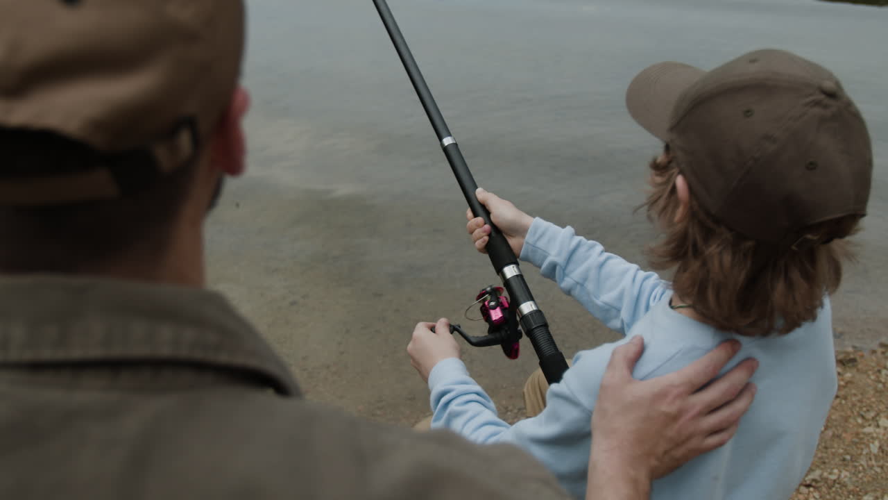 Father and son fishing together by the lake