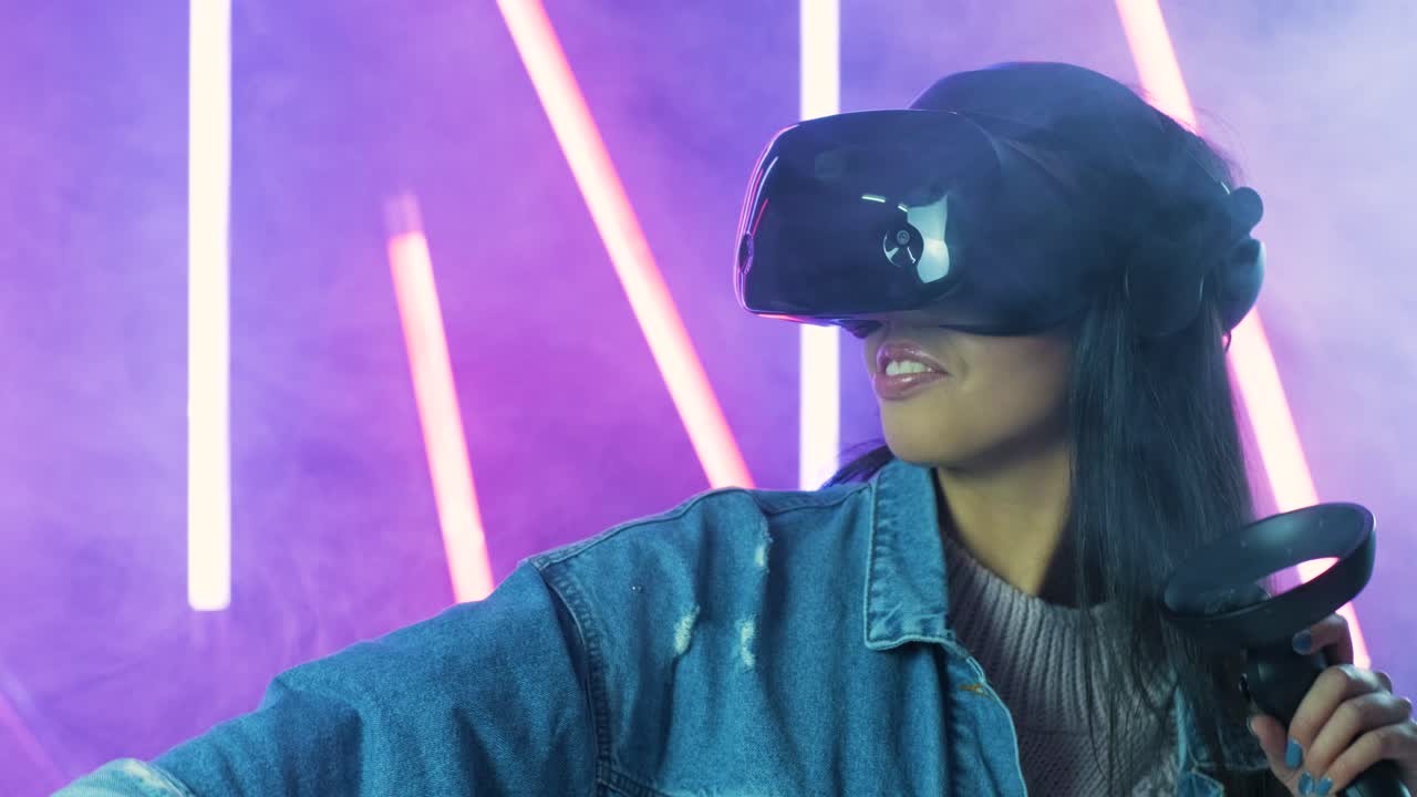 giovane donna che gioca e sorride nell'auricolare vr. casco di realtà virtuale su sfondo di luce a colori fumo
