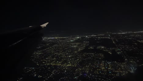 city lights seen at night from an airplane window during american airlines flight