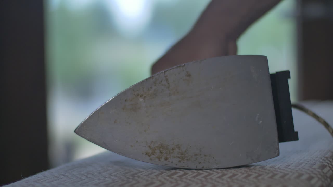 남자는 오래된 빈티지 다리미로 천을 부드럽게 한다