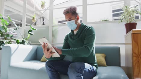hombre con máscara facial limpiando su tableta digital con un pañuelo