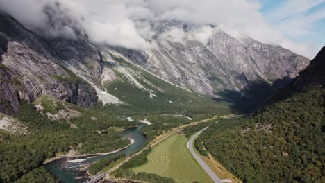 aerial footage showing the rauma river in norway, with mountains, greenery and grass