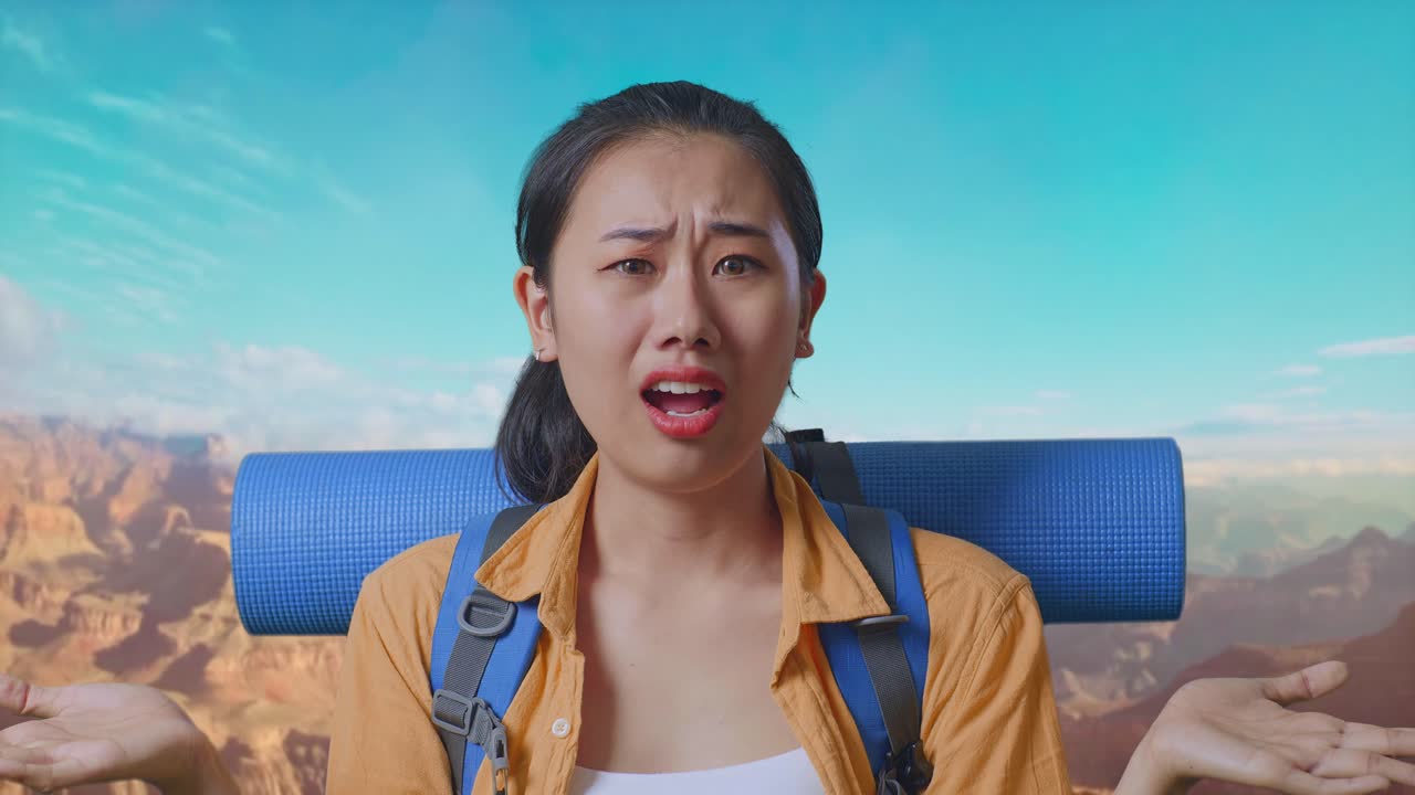 Close Up Of Puzzled Asian Female Hiker With Mountaineering Backpack Making Gestures Doubtfully And Saying Why While Traveling At The Top Of Mountain