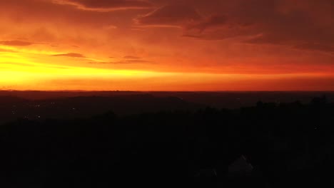 Aufsteigender-Drohnenschuss,-Der-Den-Feuerroten-Und-Orangefarbenen-Himmel-Enthüllt