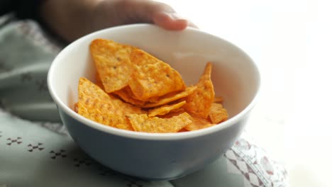 person eating tortilla chips from a bowl