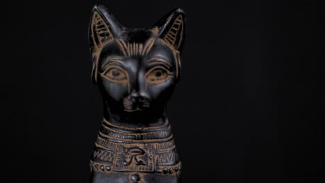 dolly of a small replica egyptian statue of bastet - facing forward - close up right to left