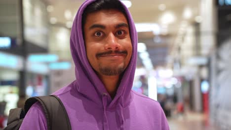 young happy man wearing hoodie inside shopping mall, front view