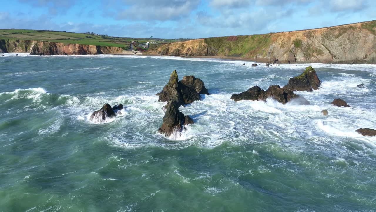 Epic Ireland drone pullback low over sea in winter storm waves and rough Atlantic seas breaking on reefs and coast at Copper Coast Waterford